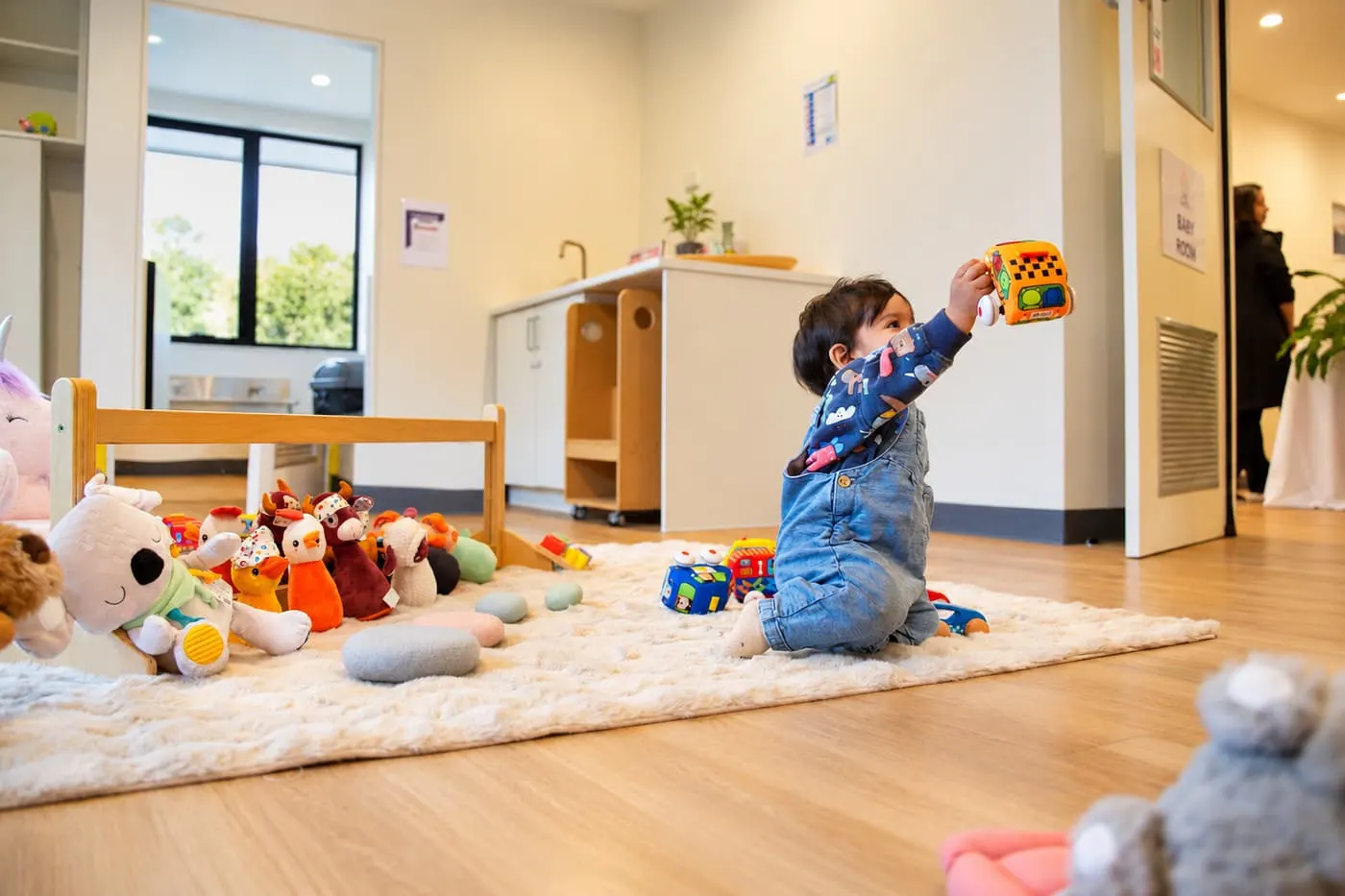 A baby playing with toys on a rug in the YoMy Sunshine nursery