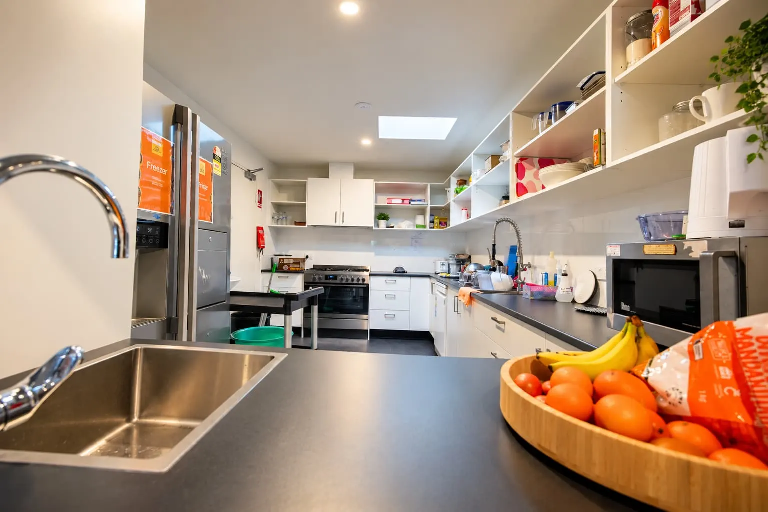 Centre kitchen with a sink, fresh fruit and open shelves of ingredients