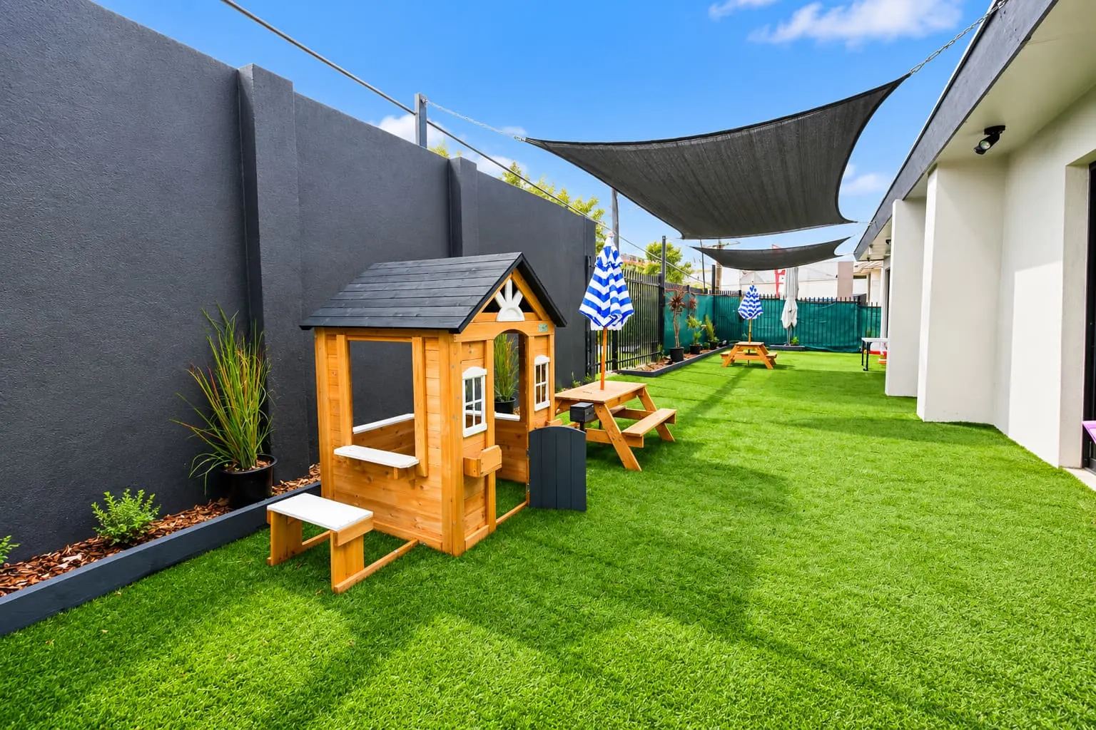 Timber cubby house on artificial grass in the fenced play area