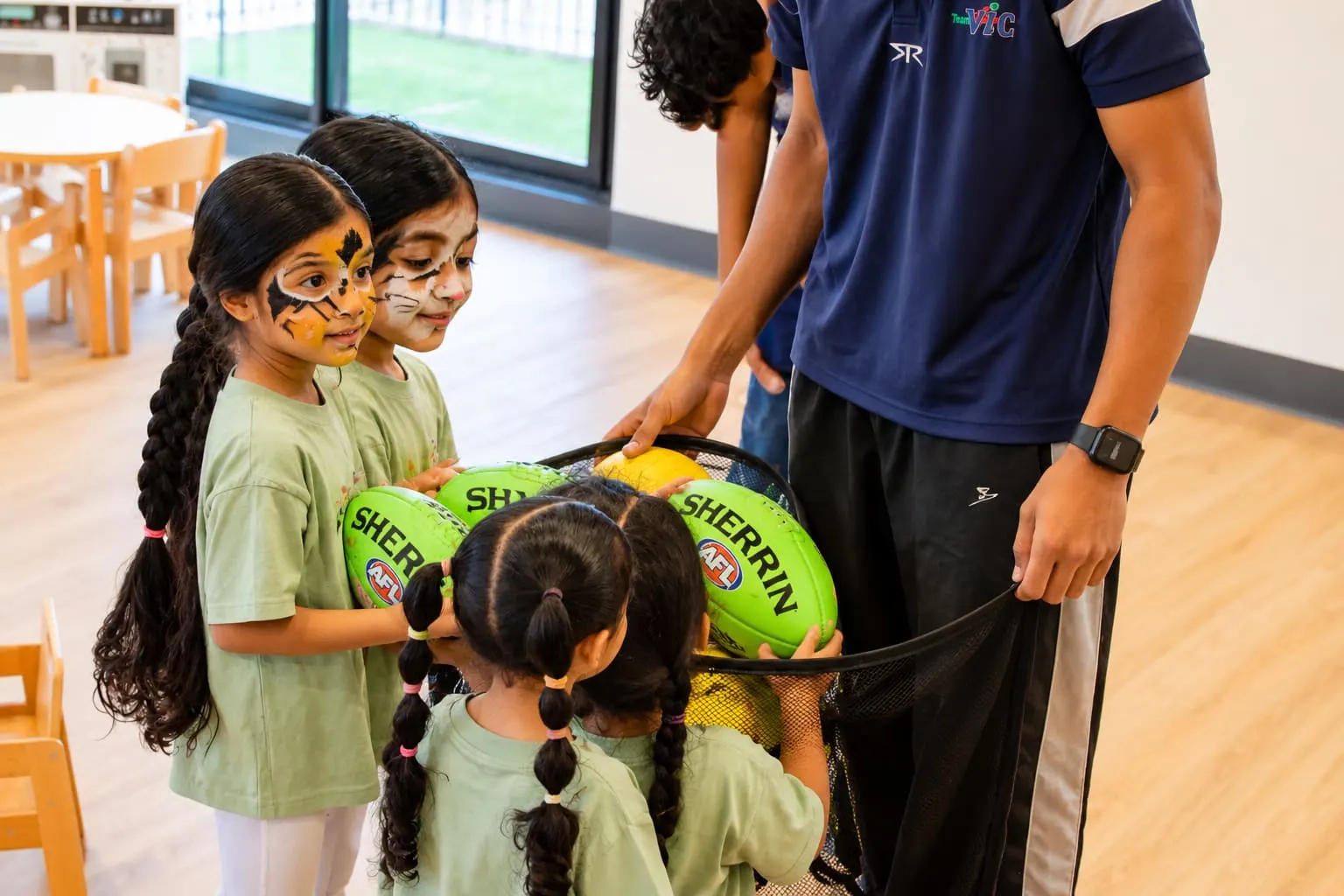 An educator and two children playing with a ball indoors