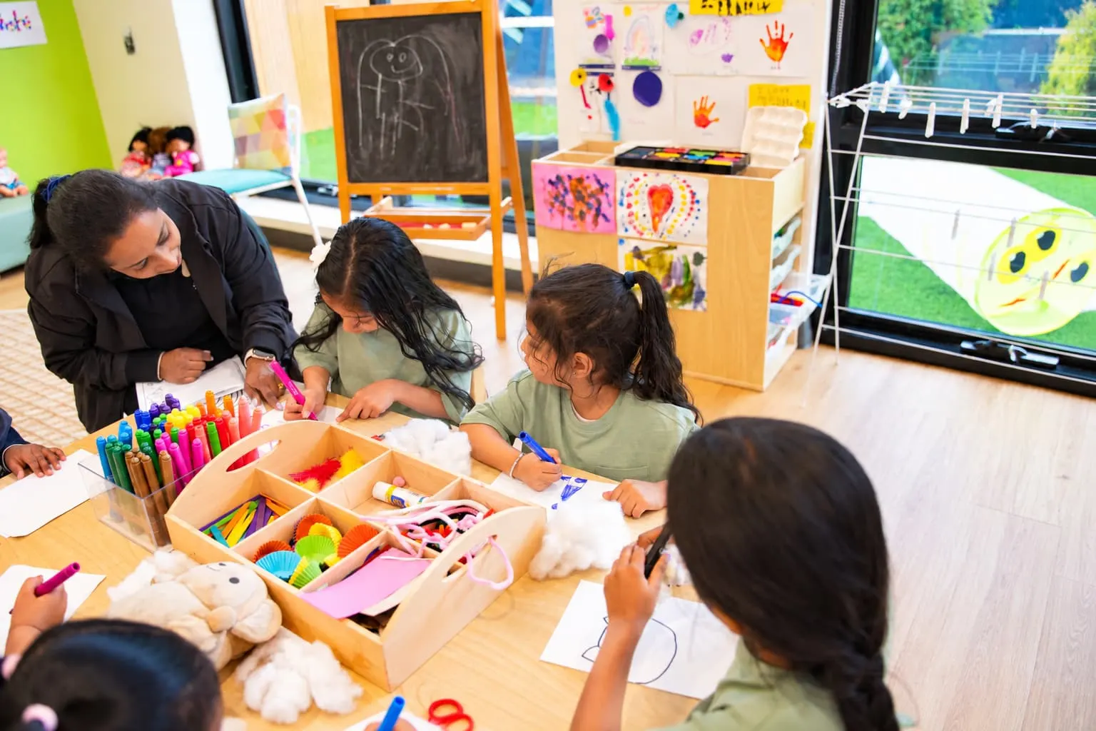 An educator and children working with craft materials at a low table