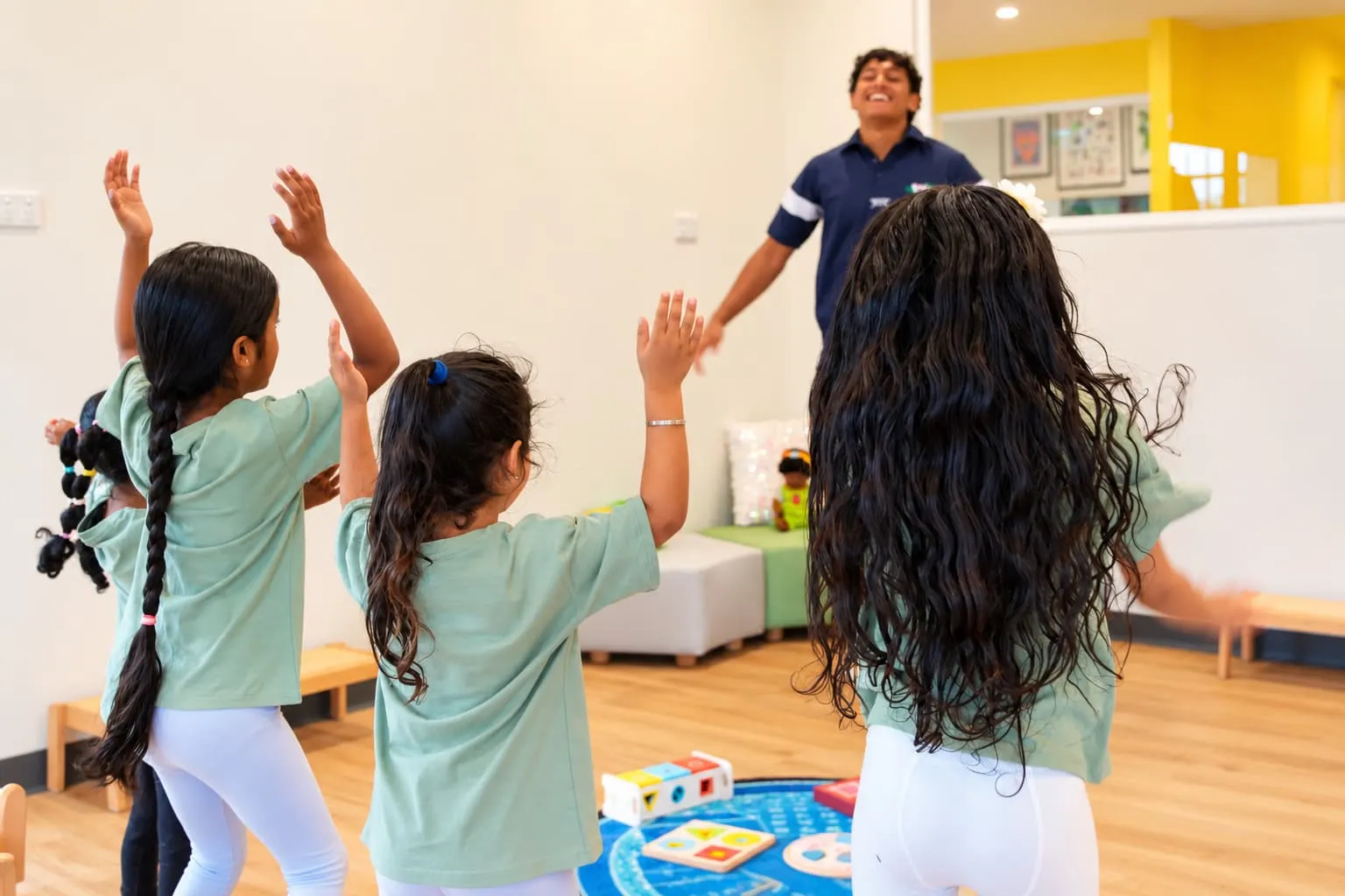 Children stretching and moving with an educator in a bright learning room at YoMy Sunshine