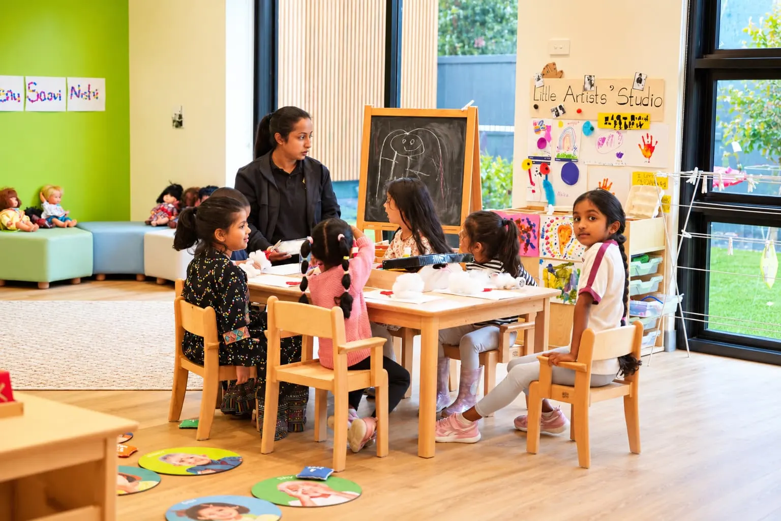 Children and an educator drawing together at a timber table